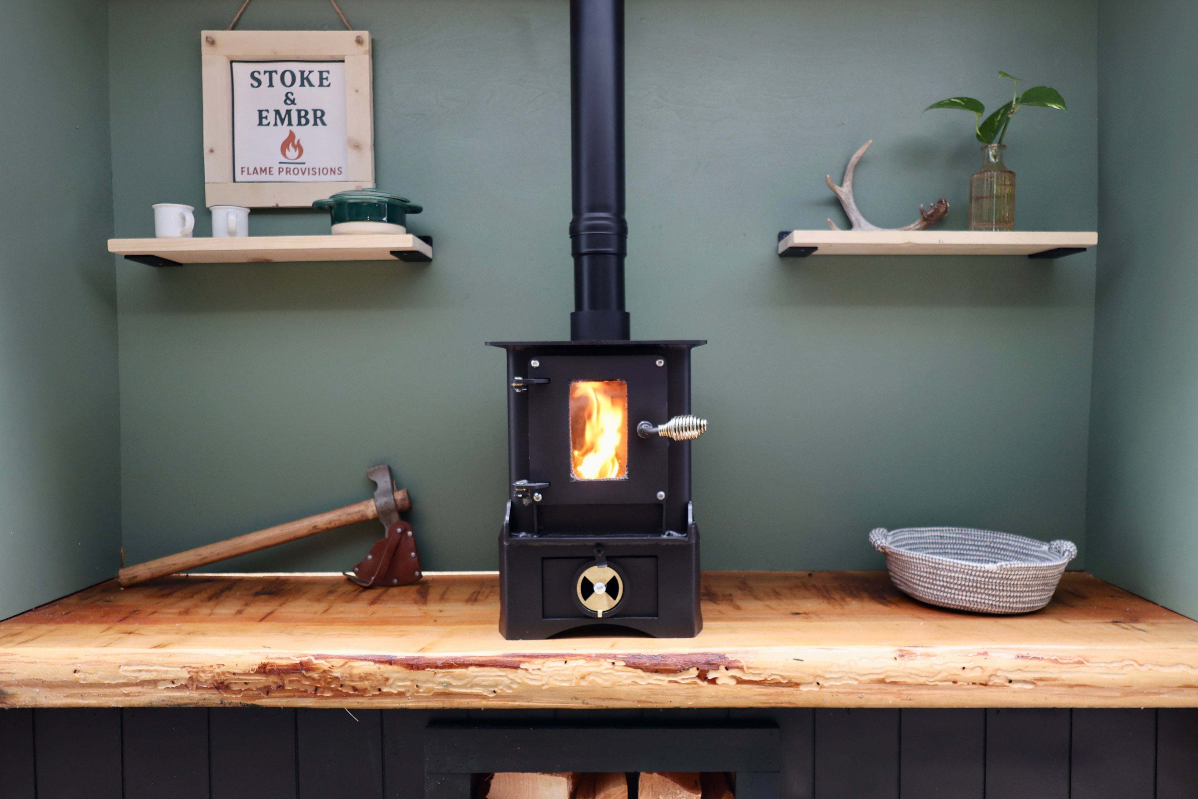 Wood-burning stove on a wooden platform with shelves and decor in the background.